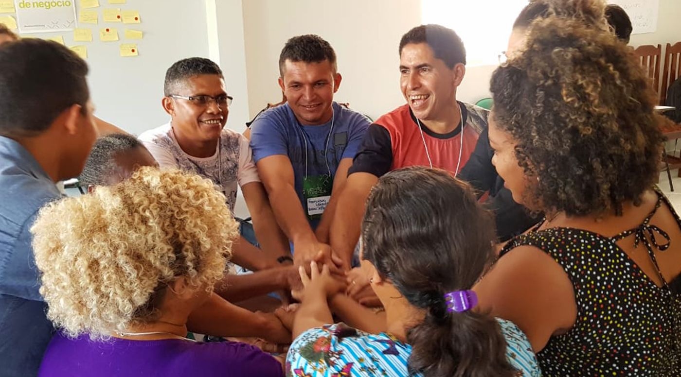 Imagem com pessoas em círculo se dando a mão e sorrindo.